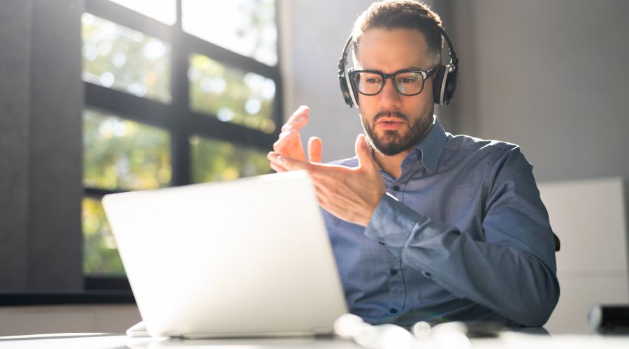 Man in front of a computer with a headset working as a virtual assistant