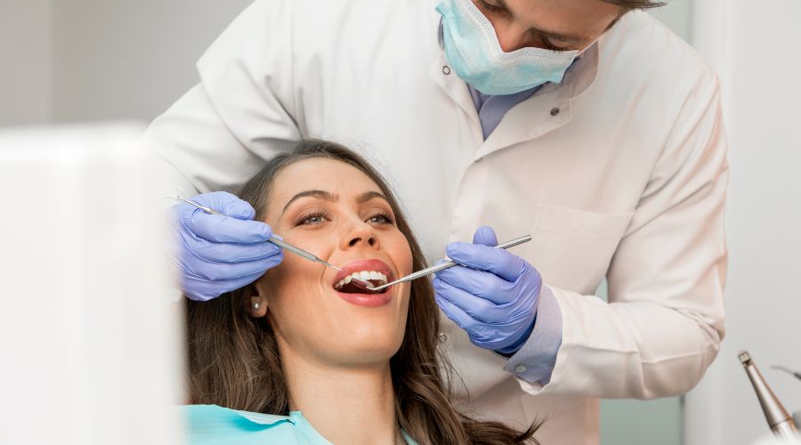 Dentist examining a patient’s teeth in a modern clinic while dictating notes to a virtual medical assistant.